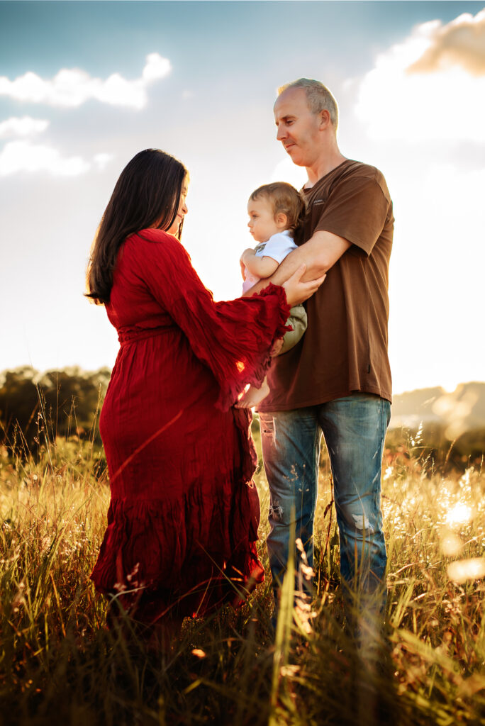 A styled family photography session in a sunlit field, with coordinated outfits capturing natural and joyful moments - Paula Jane Photography